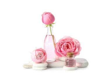 Beyaz arka planda gül özü ve çiçekli kozmetik yağı şişeleri