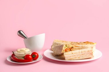 Lezzetli shawarma tabakları ve pembe arka planda domatesler.