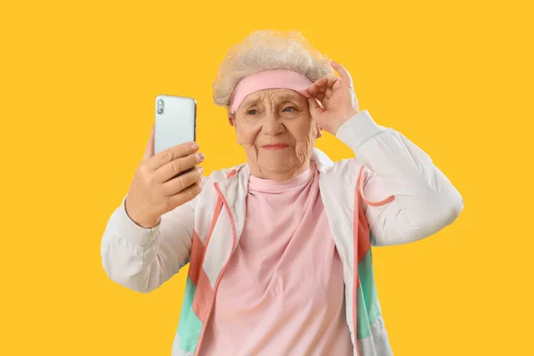 Спортивная Пожилая Женщина Мобильным Телефоном Делает Селфи Желтом Фоне — стоковое фото