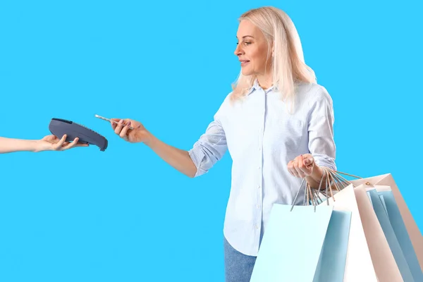Volwassen Vrouw Betalen Voor Haar Aankopen Blauwe Achtergrond — Stockfoto