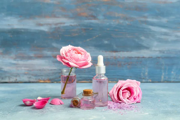 Flessen Cosmetische Olie Met Rozenextract Bloemen Blauwe Tafel — Stockfoto
