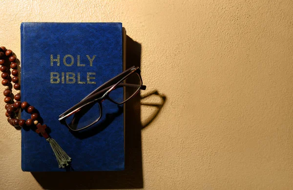 圣经上有米色背景的祈祷珠子和眼镜 — 图库照片