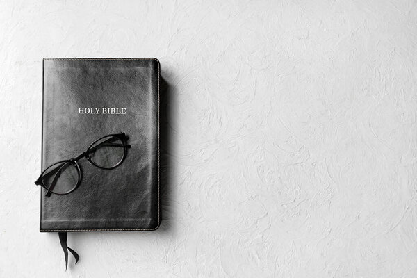 Библия с очками на сером фоне