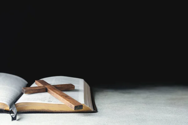 圣经上黑色背景的木制十字架 — 图库照片