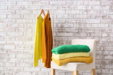 Odadaki tuğla duvarın yanında güzel kazaklı sandalye.