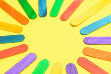 Bej arkaplanda renkli dondurma çubuklarından yapılmış çerçeve