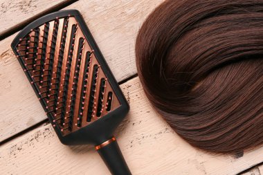 Kahverengi saçlı, bej renkli ahşap arka planda fırçalı, yakın plan.