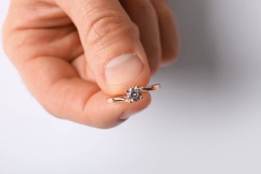 Beyaz arka planda altın nişan yüzüğü olan adam, yakın plan.