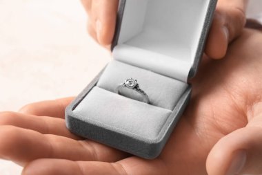 Beyaz arka planda nişan yüzüğü olan bir adam, yakın plan.