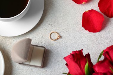 Nişan yüzüklü kutu, kahve fincanı ve beyaz arka planda güller.