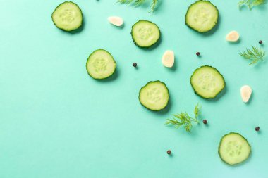 Turkuaz arka planda dereotu ve sarımsaklı salatalık dilimleri.