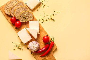 Açık sarı arka planda işlenmiş peynir, ekmek ve sebzeli pano.