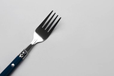 Gri arka planda plastik saplı paslanmaz çelik çatal.