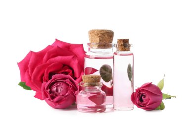 Beyaz arka planda gül özü ve çiçekli kozmetik yağı şişeleri