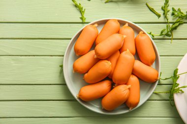 Yeşil ahşap arka planda roka ile kaynamış sosis tabağı.