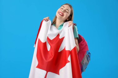 Mavi arka planda Kanada bayrağı olan genç bir kadın.