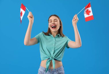 Mavi arka planda Kanada bayrakları olan genç bir kadın.