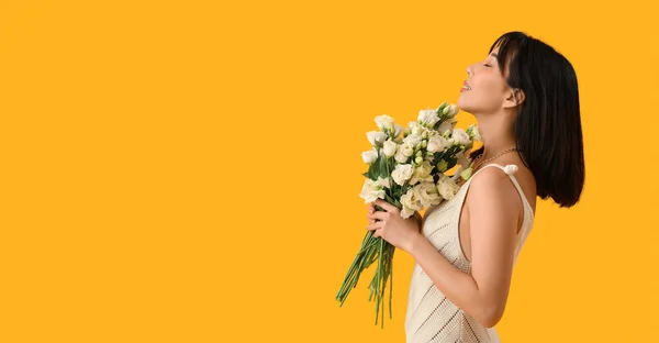 stock image Beautiful Asian woman holding bouquet of eustoma flowers on yellow background with space for text