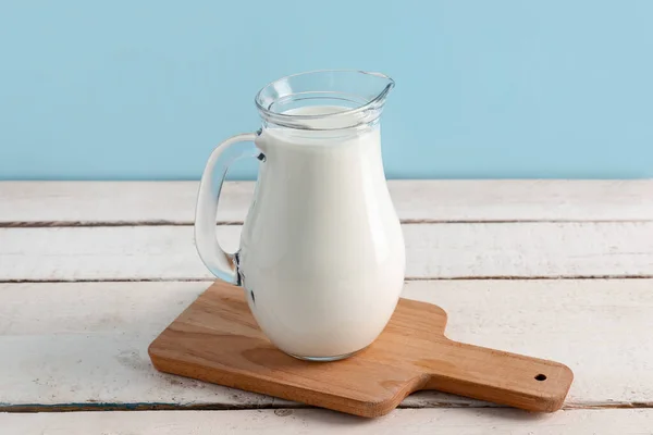 白い木製のテーブルの上に新鮮な牛乳とジャグ — ストック写真