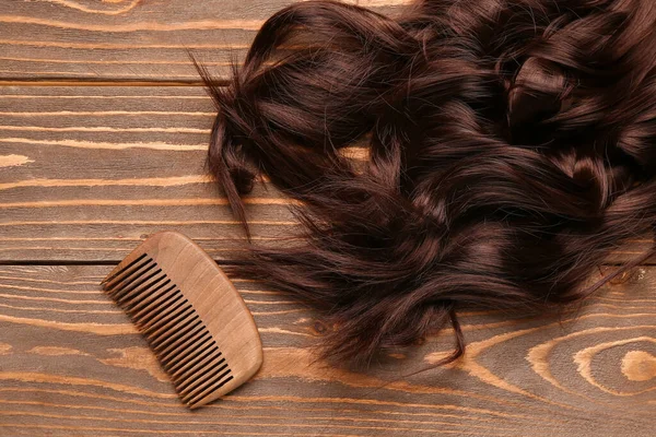 Ahşap Arka Planda Taraklı Kıvırcık Kahverengi Saçlar — Stok fotoğraf