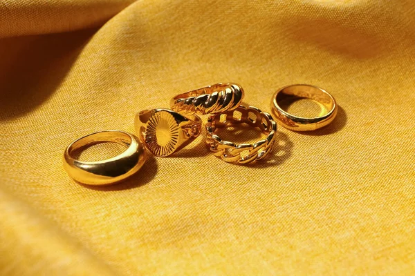 黄色面料背景上漂亮的戒指 — 图库照片