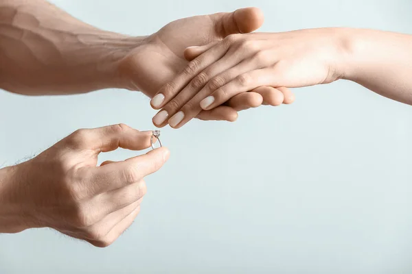 Man Putting Engagement Ring Woman Finger Light Background Closeup — Stock Photo, Image