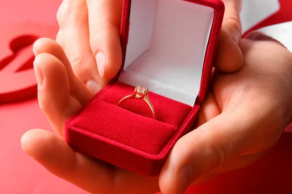 Mężczyzna Trzyma Pudełko Pierścionkiem Zaręczynowym Czerwonym Tle Zbliżenie — Zdjęcie stockowe