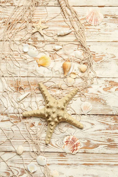 明るい木製の背景に貝殻や網を持つ美しいヒトデ — ストック写真