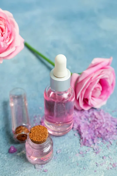 Bottles Cosmetic Oil Rose Extract Flowers Blue Table — Stock Photo, Image