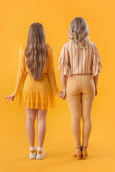 Young Sisters Holding Hands Yellow Background Back View — Stock Photo, Image