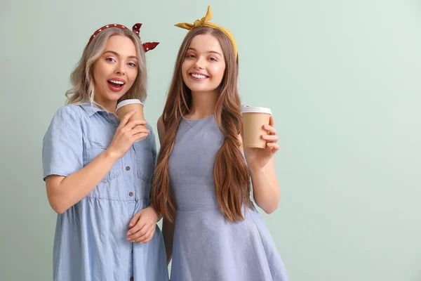 Junge Schwestern Mit Tassen Kaffee Auf Grünem Hintergrund — Stockfoto