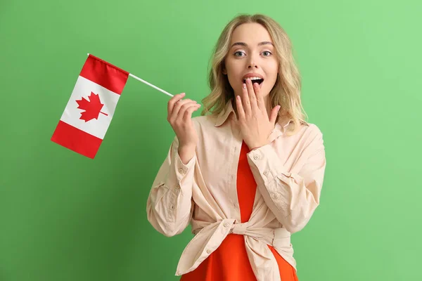 身穿绿色背景加拿大国旗的令人惊讶的年轻女子 — 图库照片