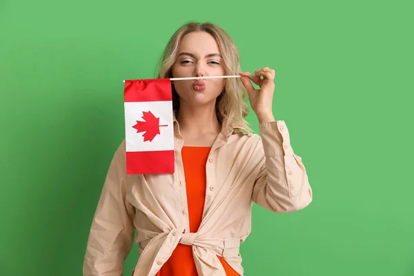 一个绿色背景上挂着加拿大国旗的有趣的年轻女子 — 图库照片