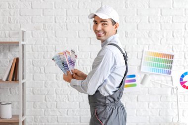Male painter with color palettes near white brick wall