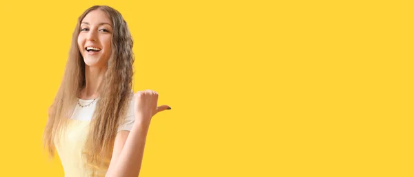 Glückliche Junge Frau Zeigt Auf Etwas Auf Gelbem Hintergrund Mit — Stockfoto