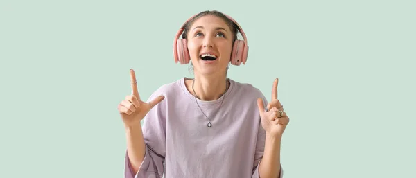Kulaklıklı Mutlu Genç Kadın Arka Plandaki Bir Şeyi Işaret Ediyor — Stok fotoğraf