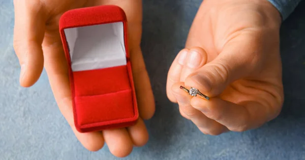 男性手牵着盒子 蓝色背景的订婚戒指 — 图库照片