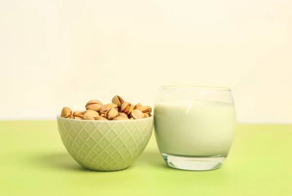 stock image Glass of healthy pistachio milk and bowl with nuts on green table