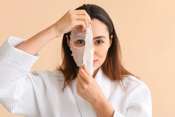 Wanita Muda Menerapkan Lembar Masker Pada Latar Beige Closeup — Stok Foto