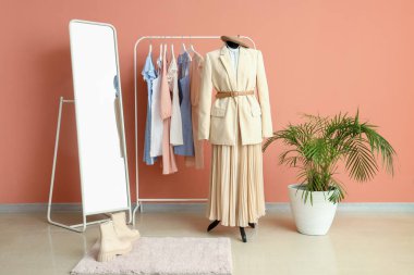 Moda tasarımcısının stüdyosunun içinde manken, raf ve giysiler var.