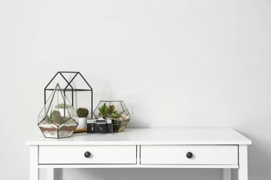 Işık duvarının yanındaki masada fotoğraf makinesi olan çiçekçiler.