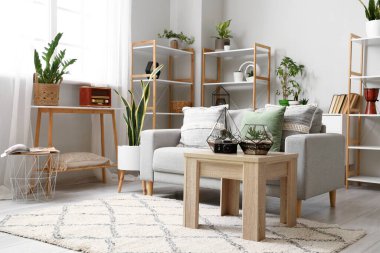 Kanepesi, çiçekleri ve çiçekleri olan aydınlık oturma odasının içinde.