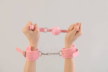 Pembe kelepçeli ve arka planda seks dükkanından ağzı tıkalı bir kadın.