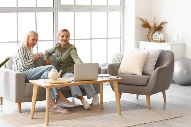 Happy mature women with laptop at home