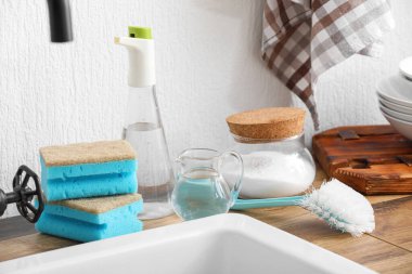 Bir şişe sirke, kabartma tozu, fırça ve süngerler lavabonun yanındaki masada.