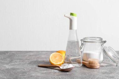 Sirke, kabartma tozu, fırça ve limonlar ışık duvarının yanındaki masada.