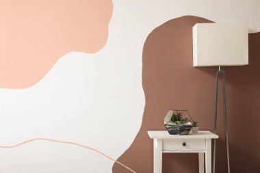 Renkli duvarın yanında masa ve lamba.