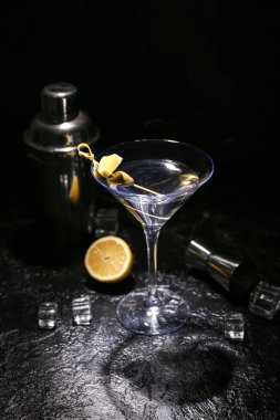 Lezzetli bir bardak martini, buz küpleri, koyu arkaplanda ölçü kabı ve titretici.