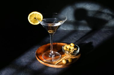 Limonlu martini ve koyu arkaplanda yeşil zeytin.