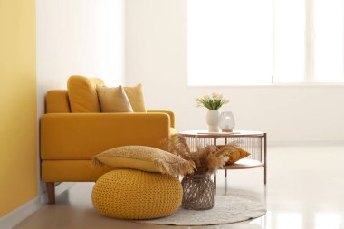 Parlak oturma odasının içinde lale çiçekleri olan rahat bir koltuk ve kahve masası.